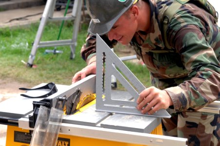 US Navy 070629-N-7088A-009 Builder 2nd Class Charles Page, assigned to Construction Battalion Maintenance Unit (CBMU) 202, adjusts a table saw while preparing to fix a fence at the Puerto Barrios Children's Hospital photo