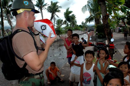 US Navy 070630-N-9421C-115 Equipment Operator 1st Class George Petrofski, attached to Amphibious Construction Battalion (ACB) 1, inflates a beach ball for local children along the Tagas River