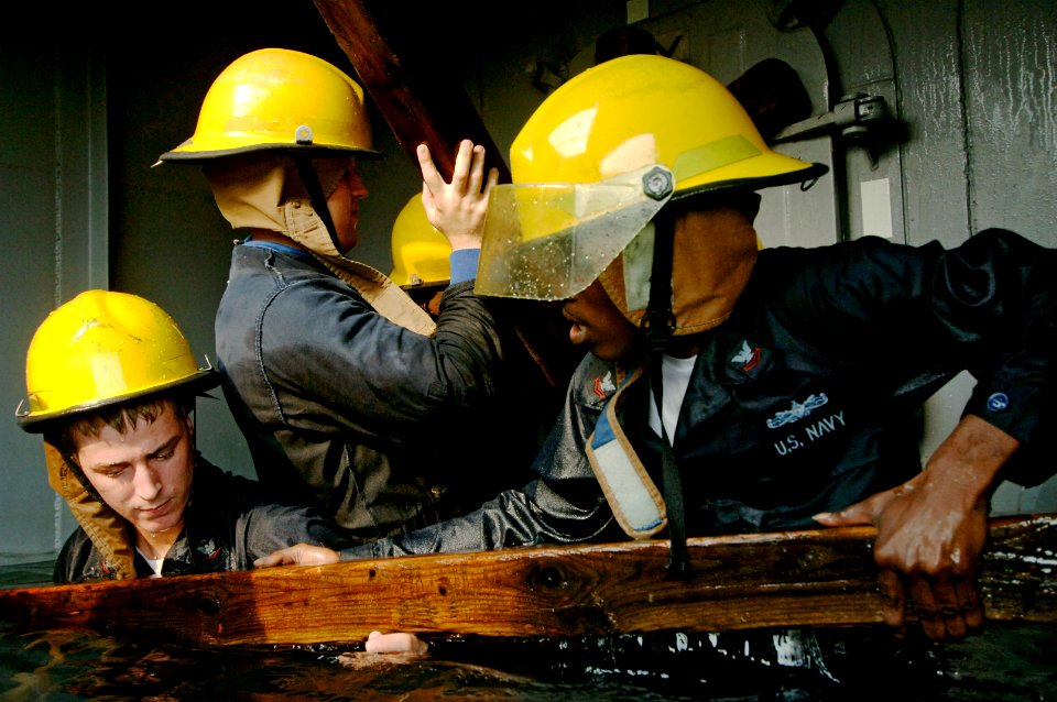 US Navy 070627-N-8148A-177 Damage Controlman 3rd Class Perry Chapman, left, assists Damage Controlman 2nd Class Marcus Taylor in a shoring exercise inside a flooded compartment of a training simulator during the 5th Annual Dama