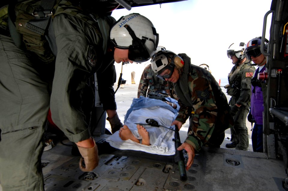 US Navy 070701-N-0194K-046 Aviation Warfare Systems Operator 2nd Class Trevor Ahrendt, from Helicopter Sea Combat Squadron (HSC) 28, assists Air Force Tech. Sgt. Michael Cooper as they place a Guatemalan patient onto an MH-60S
