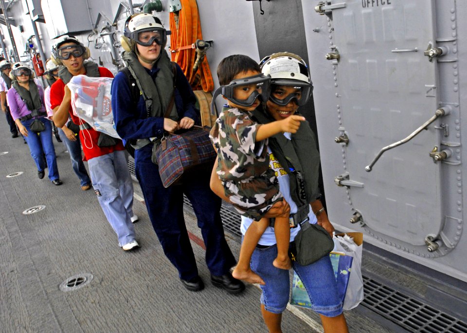 US Navy 070629-N-4954I-064 A Filipino mother holds her little boy as they walk towards a waiting helicopter on the flight deck of USS Peleliu (LHA 5), for an airlift home to Tabaco City, Philippines