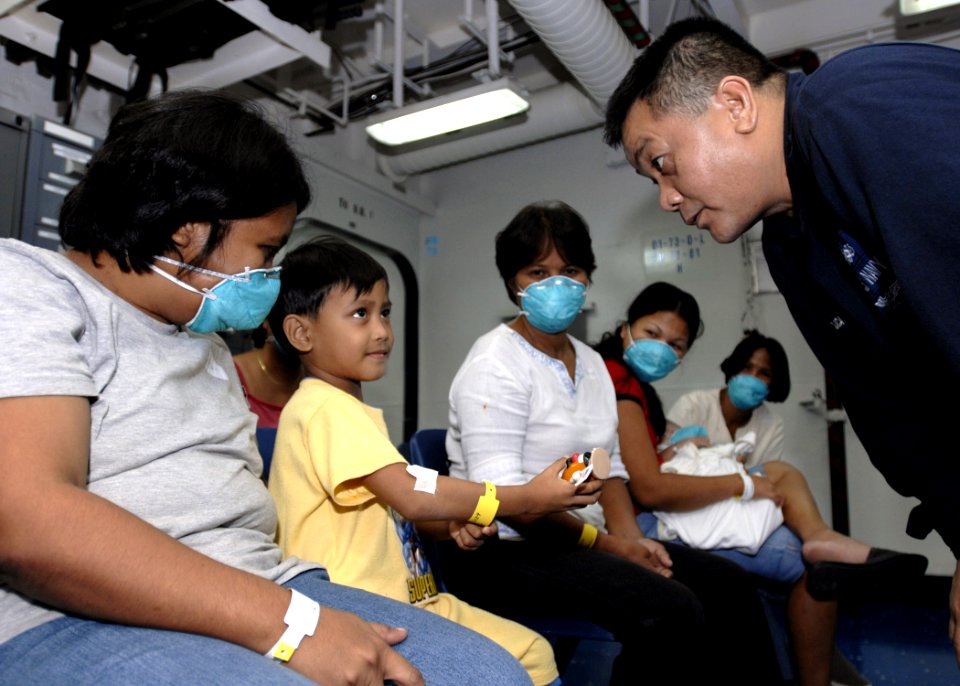 US Navy 070630-N-4954I-044 Machinist's Mate 2nd Class Astor Mojica, attached to the amphibious assault ship USS Peleliu (LHA 5), speaks with a Filipino child in the medical ward prior to surgery