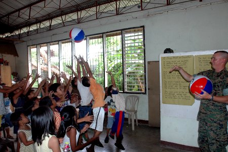 US Navy 070630-N-9421C-072 Cpl. Bobby Sullivan attached to U.S Marine Forces Pacific Band tosses a beach ball to children at Travesia Elementary School photo