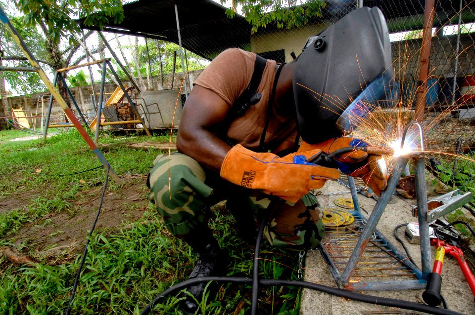 US Navy 070629-N-6278K-005 Steelworker 2nd Class Herbert Collins, assigned to the Construction Battalion Maintenance Unit (CBMU) 202, welds a loop on a swing set at Puerto Barrios Children's Hospital