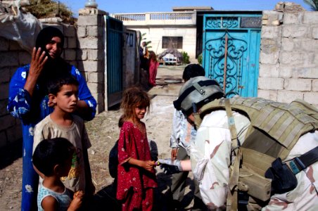 US Navy 070702-N-8298P-038 Coalition forces and Iraqi army soldiers patrol the town of Samrah and hand out candy as they inspect their local schoolhouse for future projected improvements during Operation Iraqi Freedom photo