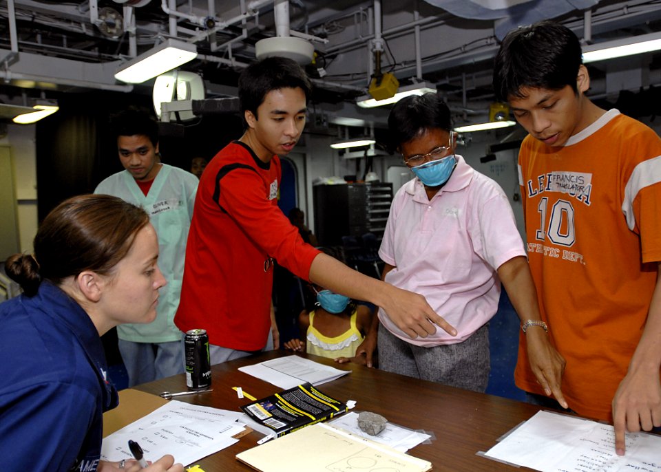 US Navy 070630-N-4954I-020 Aviation Ordnanceman 3rd Class Ashley Cameron and to two Filipino translators assist a Filipino patient during check in for medical care aboard amphibious assault ship USS Peleliu (LHA 5)