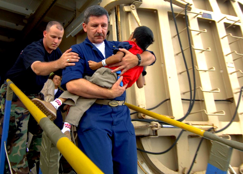 US Navy 070701-N-6278K-136 Lt. Cmdr. Karl Kish, a Navy chaplain, carries a patient off Military Sealift Command hospital ship USNS Comfort (T-AH 20) into a boat for a return home to Guatemala