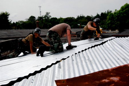 US Navy 070629-N-6278K-006 Sailors assigned to Construction Battalion Maintenance Unit (CBMU) 202, reconstruct a roof at Puerto Barrios Children's Hospital
