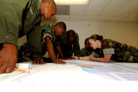 US Navy 070702-N-0989H-027 Boatswain's Mate 1st Class Brandy Sugden, Expeditionary Training Command, assists Dominican Republic soldiers with plotting courses on charts during coxswain subject matter exchanges photo
