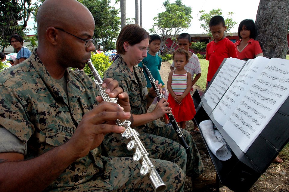 US Navy 070630-N-9421C-099 Local children watch as Cpl. David Street and Lance Cpl. Victoria Holman, both attached to the U.S Marine Forces Pacific Band, perform for patients waiting to be seen by the Pacific Partnership 2007 m