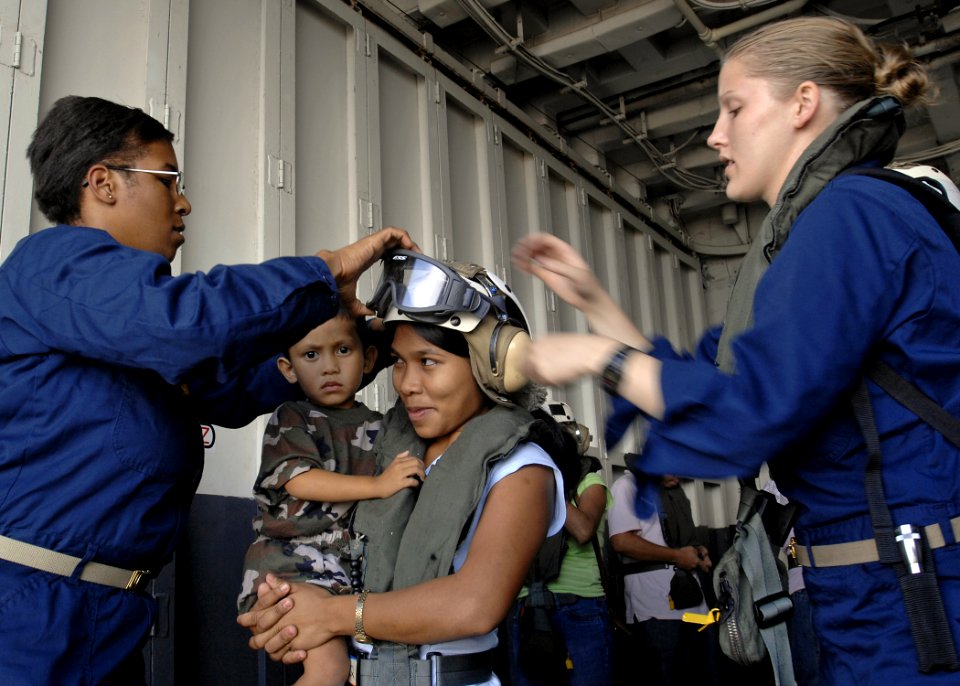 US Navy 070629-N-4954I-039 Lt. Leslie Councilor helps put a cranial on a Filipino mother as Ensign Heather Purcell-Mullins starts to pull her goggles down while waiting to board a helicopter back to Tabaco City, Philippines
