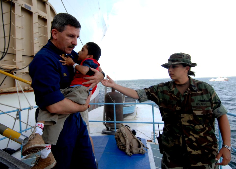 US Navy 070701-N-6278K-140 Lt. Cmdr. Karl Kish, a Navy chaplain, carries a patient into a boat for return home to Guatemala from Military Sealift Command hospital ship USNS Comfort (T-AH 20)
