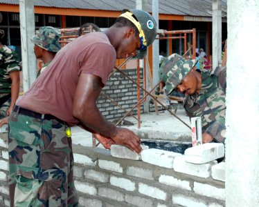 US Navy 070704-N-7783B-001 Builder 3rd Class Sean Brinson, attached to Naval Mobile Construction Battalion (NMCB) 7, helps build a new schoolhouse with the assistance of a member of the Royal Malaysian Army Engineers at a engin photo