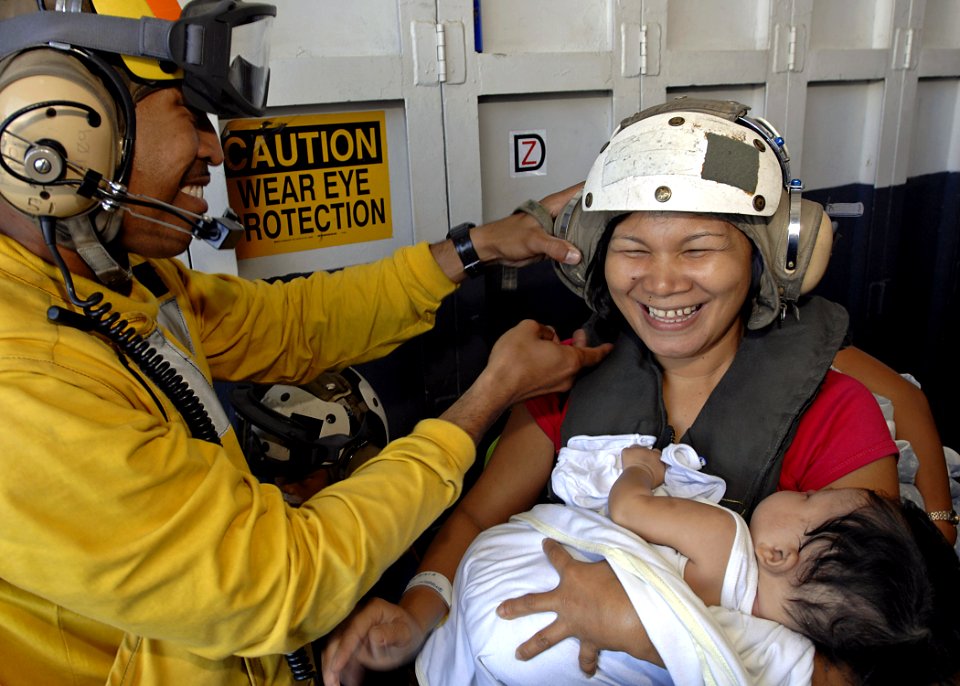 US Navy 070702-N-4954I-028 Aviation Boatswain's Mate Handling 1st Class Lawrence Salalila helps put a cranial on a Filipino mother prior to an airlift from USS Peleliu (LHA 5)