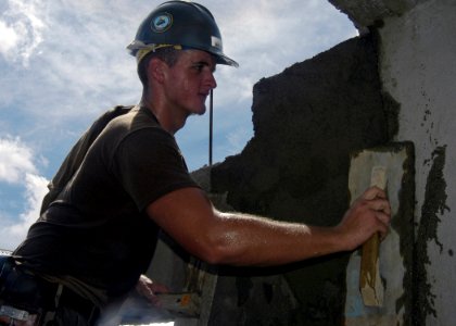 US Navy 070703-N-1752H-055 Builder 3rd Class Jerry Morgan, of Amphibious Construction Battalion (ACB) 1, applies mortar to a house being built at the Honest Anislag Duraga Transition Center in support of Pacific Partnership 200