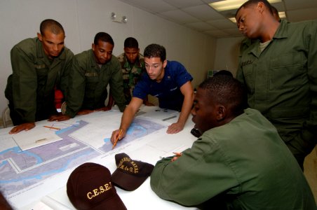 US Navy 070702-N-0989H-016 Boatswain's Mate 1st Class Ernest Ramos, U.S. Coast Guard International Training Division, assists Dominican Republic soldiers with plotting courses on charts during coxswain subject matter exchanges photo