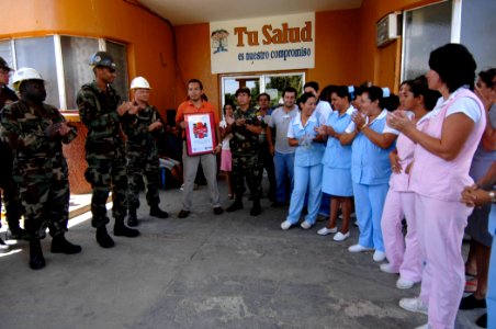 US Navy 070701-N-6278K-061 Members of Construction Battalion Maintenance (CBMU) 202 present Puerto Barrios Children's Hospital with a poster illustrating Comfort humanitarian efforts at various sites throughout Guatemala
