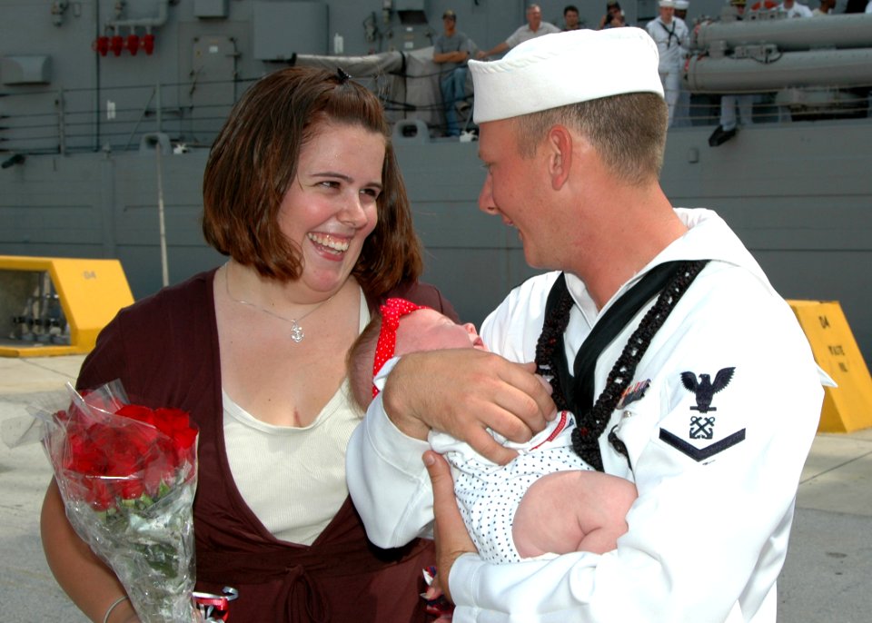 US Navy 070702-N-1522S-072 Boatswain's Mate 3rd Class Christopher Ball, joined by his wife, holds his newborn baby for the first time during the homecoming of guided-missile frigate USS Underwood (FFG 36)