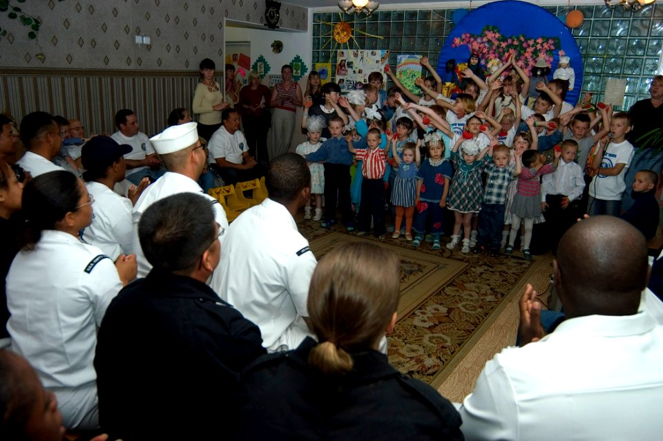 US Navy 070702-N-5253W-001 Sailors from guided-missile destroyer USS Curtis Wilbur (DDG 54) and submarine tender USS Frank Cable (AS 40) enjoy a song performed by children at the Parus Nadezhdy Children's Rehabilitation Center