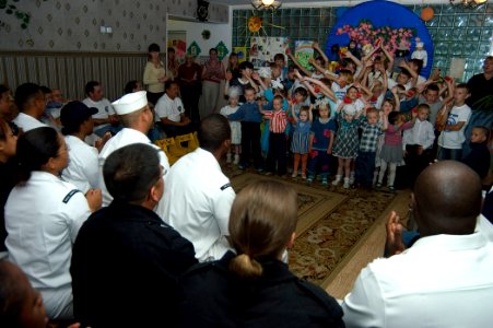 US Navy 070702-N-5253W-001 Sailors from guided-missile destroyer USS Curtis Wilbur (DDG 54) and submarine tender USS Frank Cable (AS 40) enjoy a song performed by children at the Parus Nadezhdy Children's Rehabilitation Center