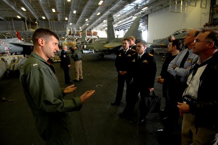 US Navy 070704-N-7883G-064 Lt. j.g. Andrew Babakan, assigned to the Diamondbacks of Strike Fighter Attack Squadron (VFA) 102, explains the various types of aircraft in the hangar bay to Australian visitors aboard USS Kitty Hawk