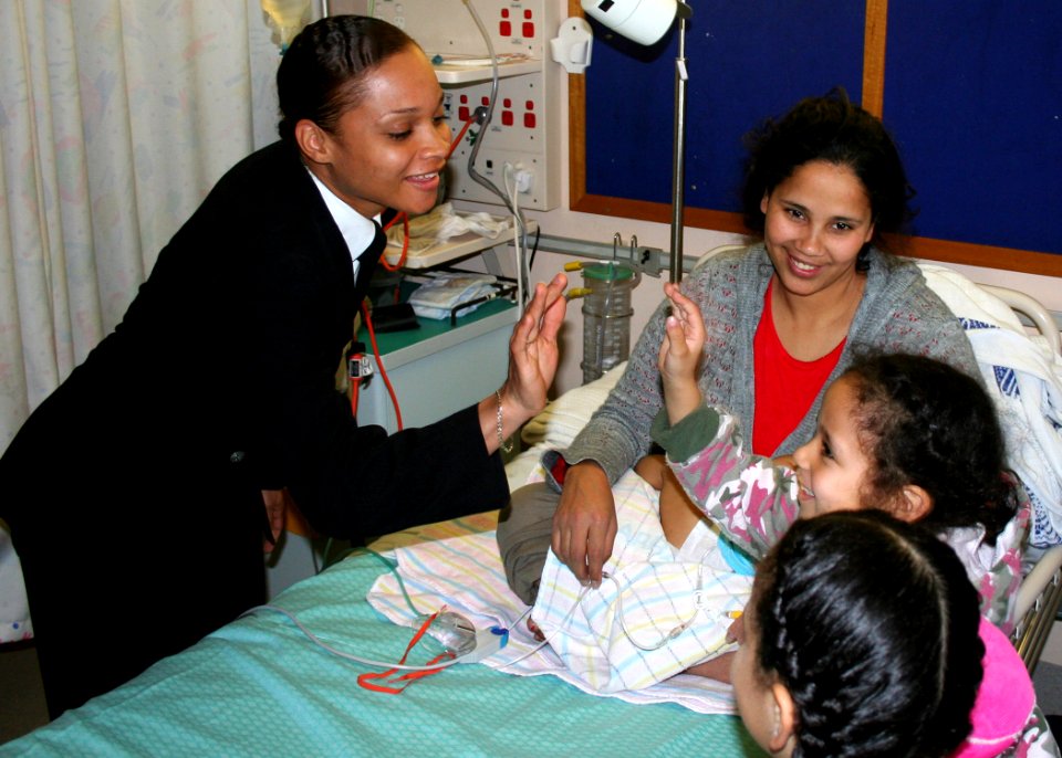US Navy 070706-N-6710M-015 Storekeeper 2nd Class Ernestine G. Burton gives a high five to a child from Sydney's Children's Hospital while participating in a community relations project during a four-day port visit