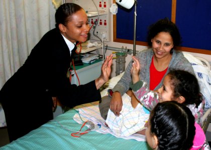 US Navy 070706-N-6710M-015 Storekeeper 2nd Class Ernestine G. Burton gives a high five to a child from Sydney's Children's Hospital while participating in a community relations project during a four-day port visit photo