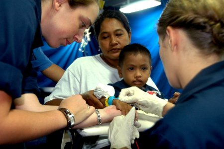 US Navy 070702-N-9421C-002 Ensign Katherine Phillips from the Naval Medical Center, San Diego, prepares to administer an IV to a Filipino child while Hospital Corpsman 3rd Class Barbara Linerooth comforts him before going into