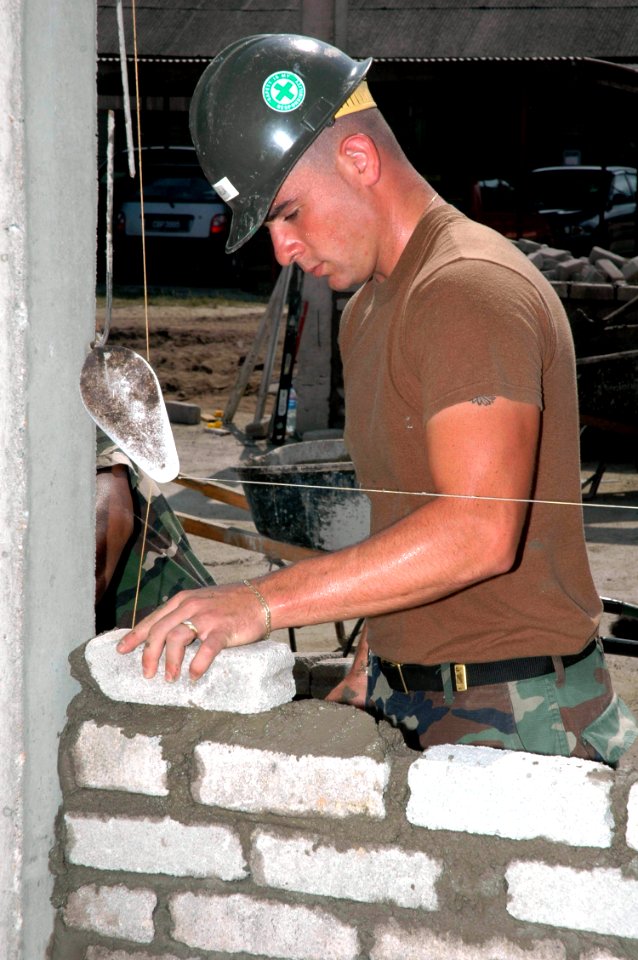 US Navy 070704-N-7783B-006 Construction Electrician Constructionman Recruit Jerry Villa, attached to Naval Mobile Construction Battalion (NMCB) 7, lays bricks while building a wall for a new classroom at a engineering civic act