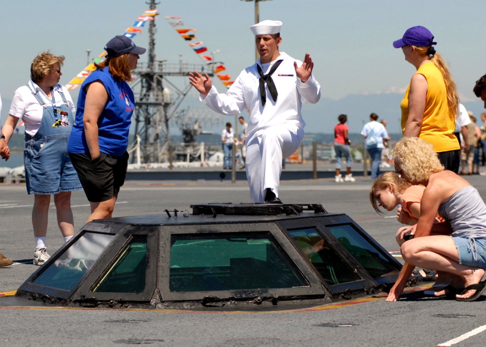 US Navy 070704-N-7981E-162 Aviation Boatswain's Mate (Equipment) Airman Corey Roudebush explains the purpose of the ship's catapult control system to a group of visitors on the flight deck of Nimitz-class aircraft carrier USS A