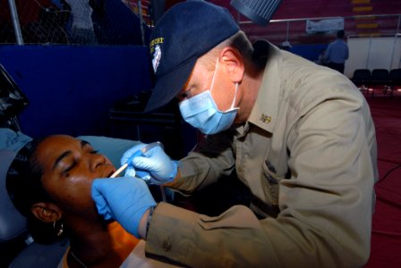 US Navy 070706-N-8704K-035 Command Master Chief Ken Day, attached to Military Sealift Command hospital ship USNS Comfort (T-AH 20), performs dental care for Saranara Chevantes at the Paul Brown Arena photo