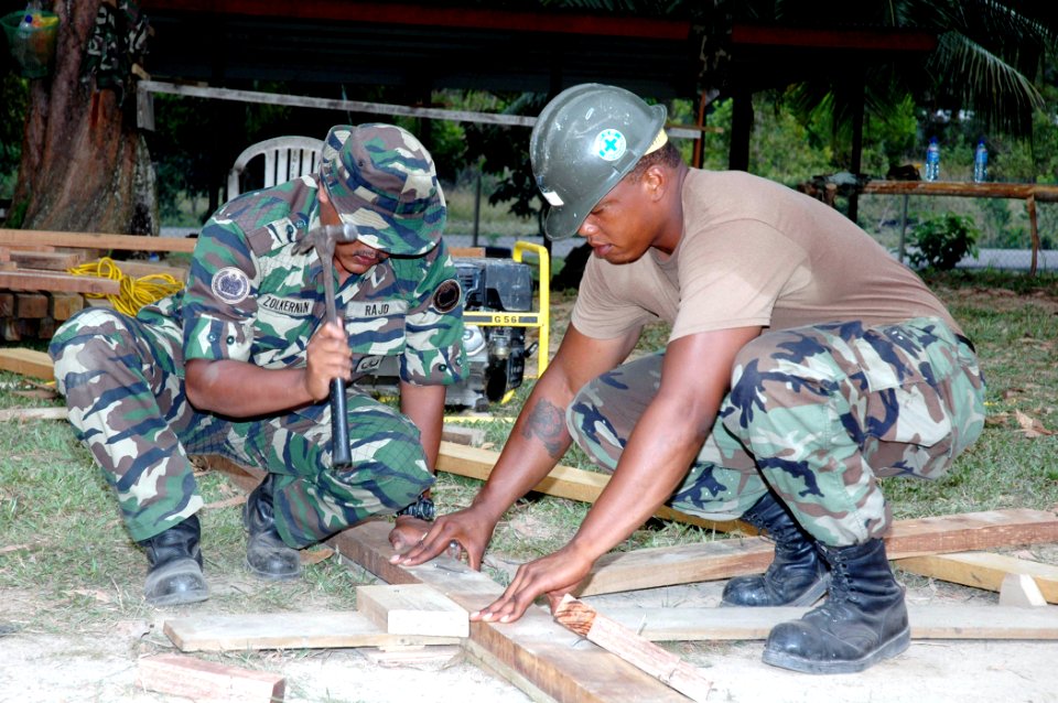 US Navy 070705-N-7783B-004 Builder 3rd Class Germaine Blair helps a Royal Malaysian Army Engineer construct a roof support for a new schoolhouse that is being build for the Sekolah Kebangsaan Meraga Beris elementary school