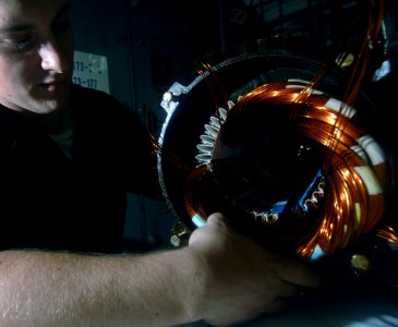 US Navy 070707-N-0535P-009 Electrician's Mate Fireman Sean Wickelgren repairs copper coils in the motor of a water pump aboard Nimitz-class aircraft carrier USS Harry S. Truman (CVN 75)