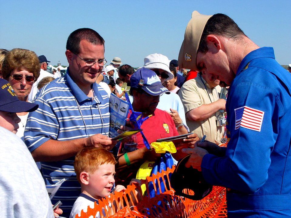 US Navy 070707-N-2888Q-003 Lt. Cmdr. Tom Winkler, a Blue Angels pilot, autographs a ballcap for a young fan following a performance at the Thunder Over Michigan Air Show