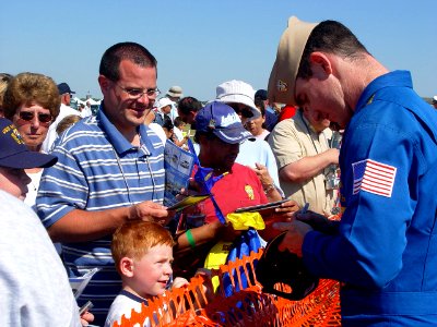US Navy 070707-N-2888Q-003 Lt. Cmdr. Tom Winkler, a Blue Angels pilot, autographs a ballcap for a young fan following a performance at the Thunder Over Michigan Air Show