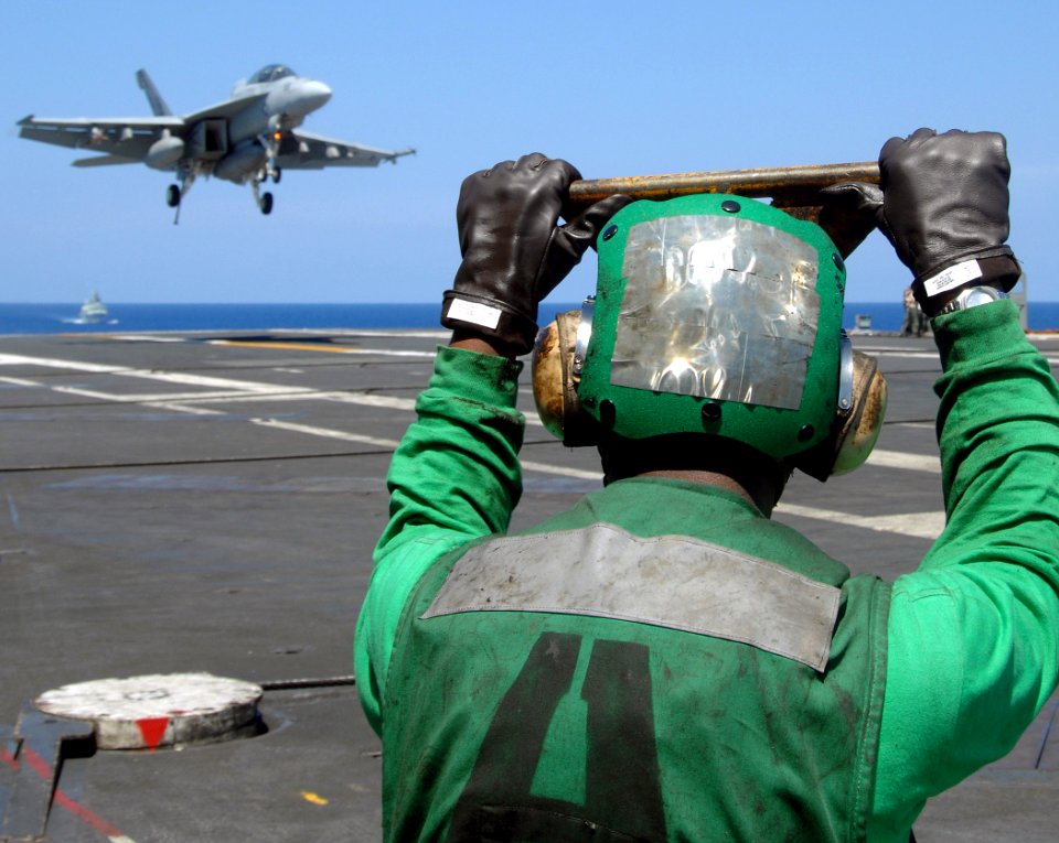 US Navy 070710-N-8923M-192 Aviation Boatswain's Mate Equipment Airman Benjamin Shaw stands by to lead the arresting wire back into the flight deck as an F-A-18F Super Hornet prepares to make an arrested recovery
