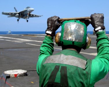 US Navy 070710-N-8923M-192 Aviation Boatswain's Mate Equipment Airman Benjamin Shaw stands by to lead the arresting wire back into the flight deck as an F-A-18F Super Hornet prepares to make an arrested recovery