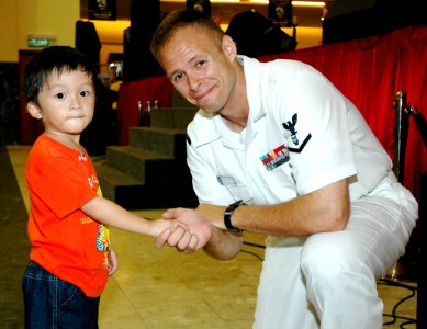 US Navy 070707-N-7783B-003 Musician 3rd Class Spence Haasenritter takes a time out during a performance with the 7th Fleet rock band Orient Express to meet with a young fan