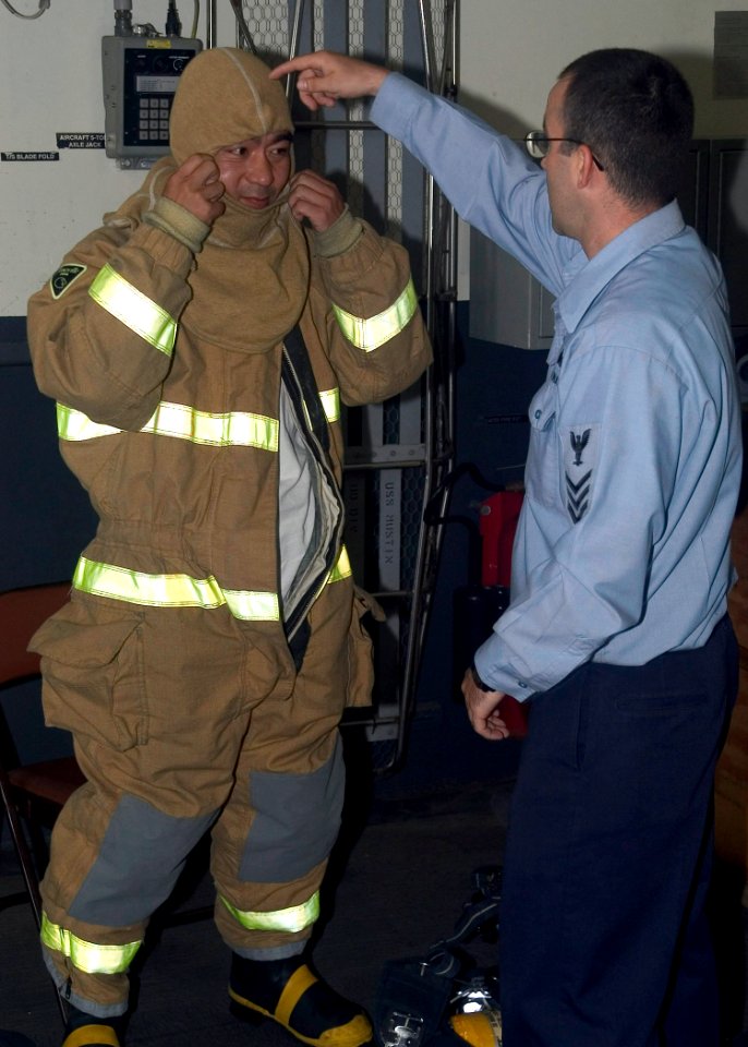 US Navy 070706-N-0483B-003 A Sailor aboard Arleigh Burke-class guided-missile destroyer USS Mustin (DDG 89) assists a Yokosuka local on how to properly don firefighting equipment during the Mustin's Family and Friend Day Cruise