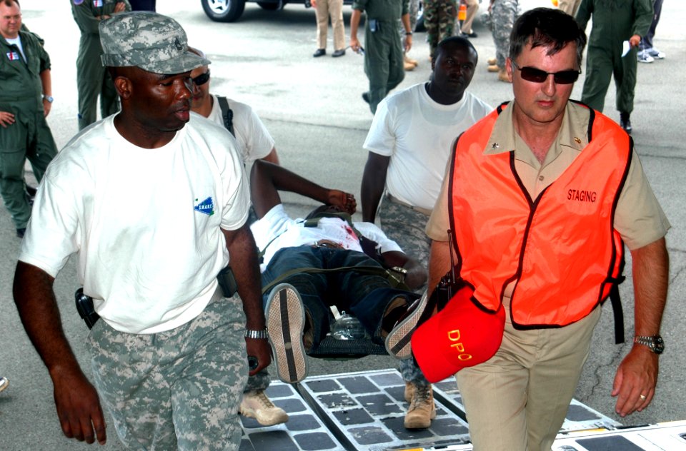 US Navy 070710-N-9758L-052 Members of the U.S. Army and U.S. Navy bring an injured medical casualty on board a Coast Guard C-130 aircraft in order to conduct necessary in-flight medical treatment during Operation Lightning Resc