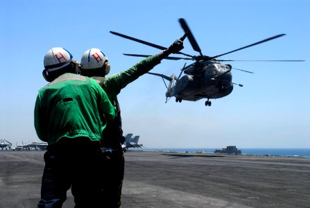 US Navy 070716-N-0890S-068 Airman Marco Arreolalegarda steadies Airman Jade Daniel as she signals to the pilots of an MH-53C Sea Dragon, assigned to the Blackhawks of Helicopter Mine Countermeasure Squadron (HM) 15, as it takes