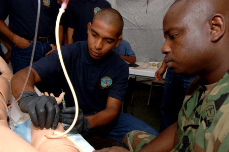 US Navy 070712-N-0989H-061 Hospital Corpsman 1st Class Charles Givens, Task Group 40.9 independent duty corpsman, and interpreter Master-at-Arms 1st Class Hector Cardona demonstrate the proper procedures for administering an IV photo