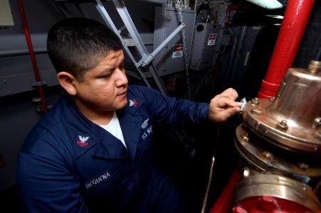 US Navy 070717-N-5387K-007 Aviation Boatswain's Mate (Fuel) 2nd Class Jose Requena polishes an installed fire fighting system while cleaning aboard USS Kitty Hawk (CV 63)