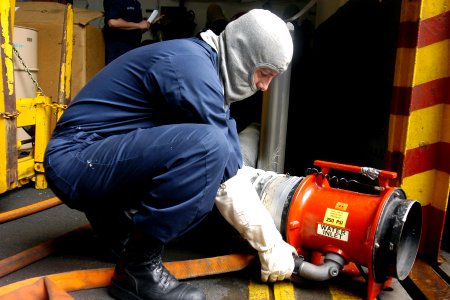 US Navy 070713-N-9195K-028 Aviation Electrician's Mate 1st Class Daniel Halsey removes a fire hose from a ram fan after completing a damage control training team drill aboard amphibious assault ship USS Peleliu (LHA 5) photo