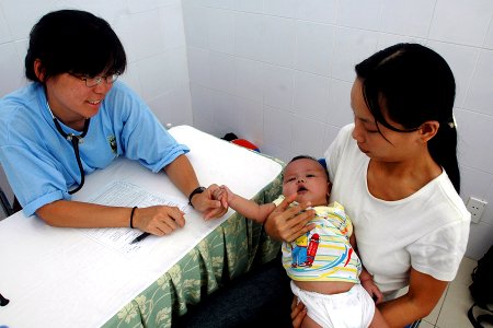 US Navy 070717-N-9421C-015 Cmdr. Con Yee Ling discusses the condition of a baby to his mother at Ngu Hanh Son District Medical Center in Da Nang, Vietnam photo