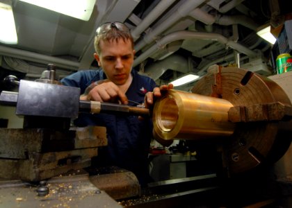 US Navy 070716-N-1226D-074 Machinery Repairman 2nd Class Kevin Mech uses a lathe to make a line shaft-bearing socket in the machine shop aboard amphibious assault ship USS Bonhomme Richard (LHD 6)