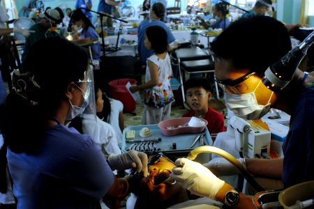 US Navy 070716-N-9195K-052 Kenny Kwon, a volunteer from the University of California at San Diego's Pre-Dental Society, assists Dr. Hoang Thu Ha, a dentist with the East Meets West Foundation, as he places sealant on a lo