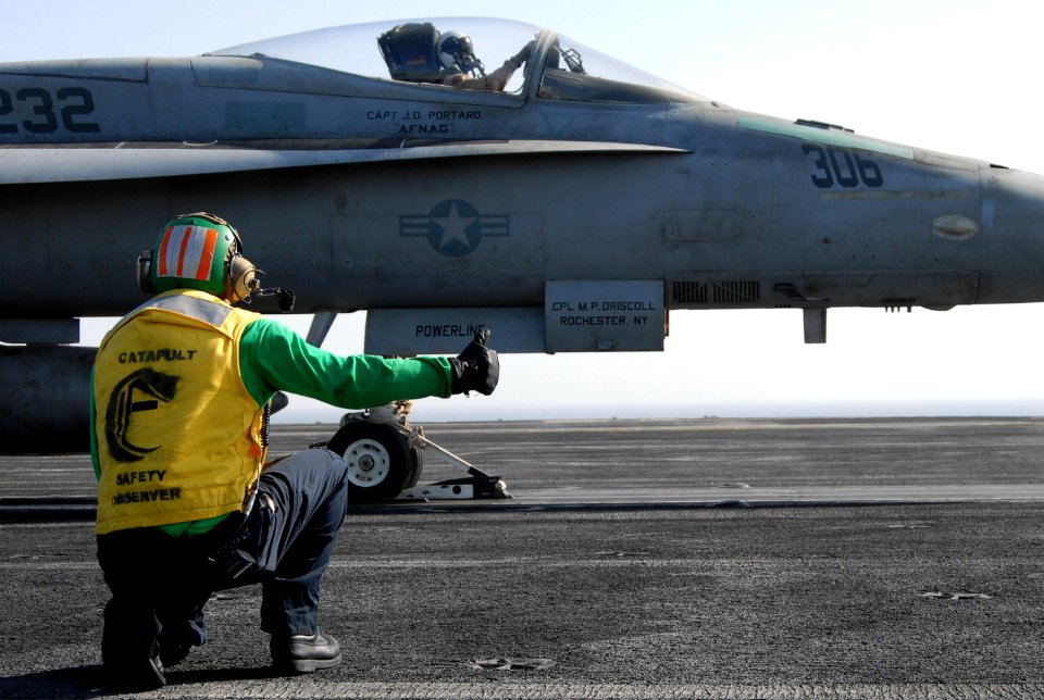 US Navy 070718-N-8119R-071 Aviation Boatswain's Mate (Electrician) 2nd Class Abraham Lopez gives the signal to launch an F-A-18A Hornet