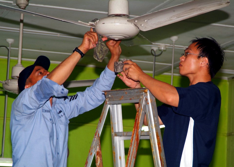 US Navy 070719-N-0120A-042 Dock landing ship USS Harpers Ferry (LSD 49) Sailor and a Singapore navy sailor work together cleaning fans at a Movement for the Intellectually Disabled of Singapore (MINDS) training and development