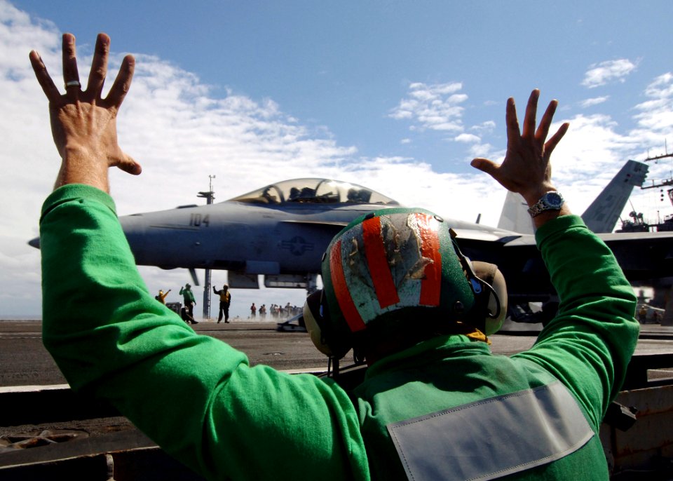 US Navy 070718-N-5928K-001 Deck edge operator Aviation Boatswain's Mate (Equipment) 1st Class Shawn Badley signals his hands are clear after launching an F-A-18F Super Hornet